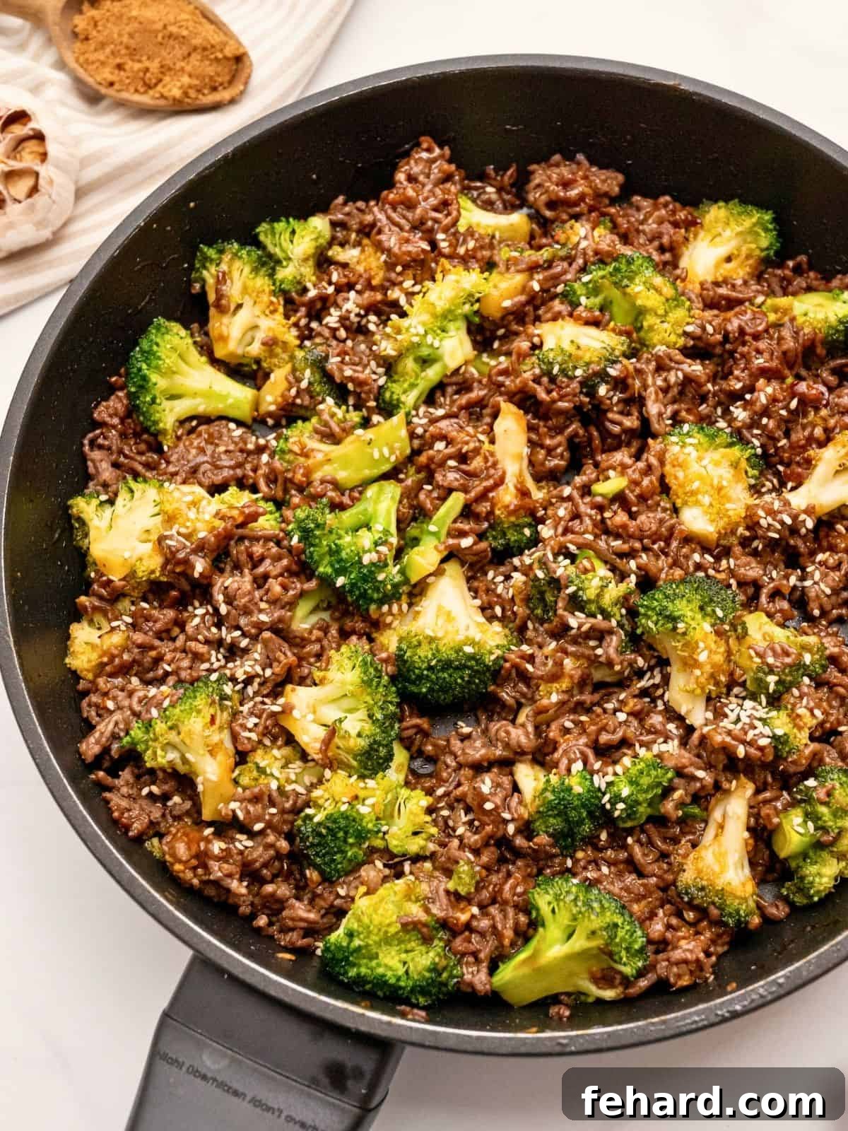 Sautéed ground beef with crisp tender broccoli tossed with sweet and savory sauce in sauté pan topped with sesame seeds.