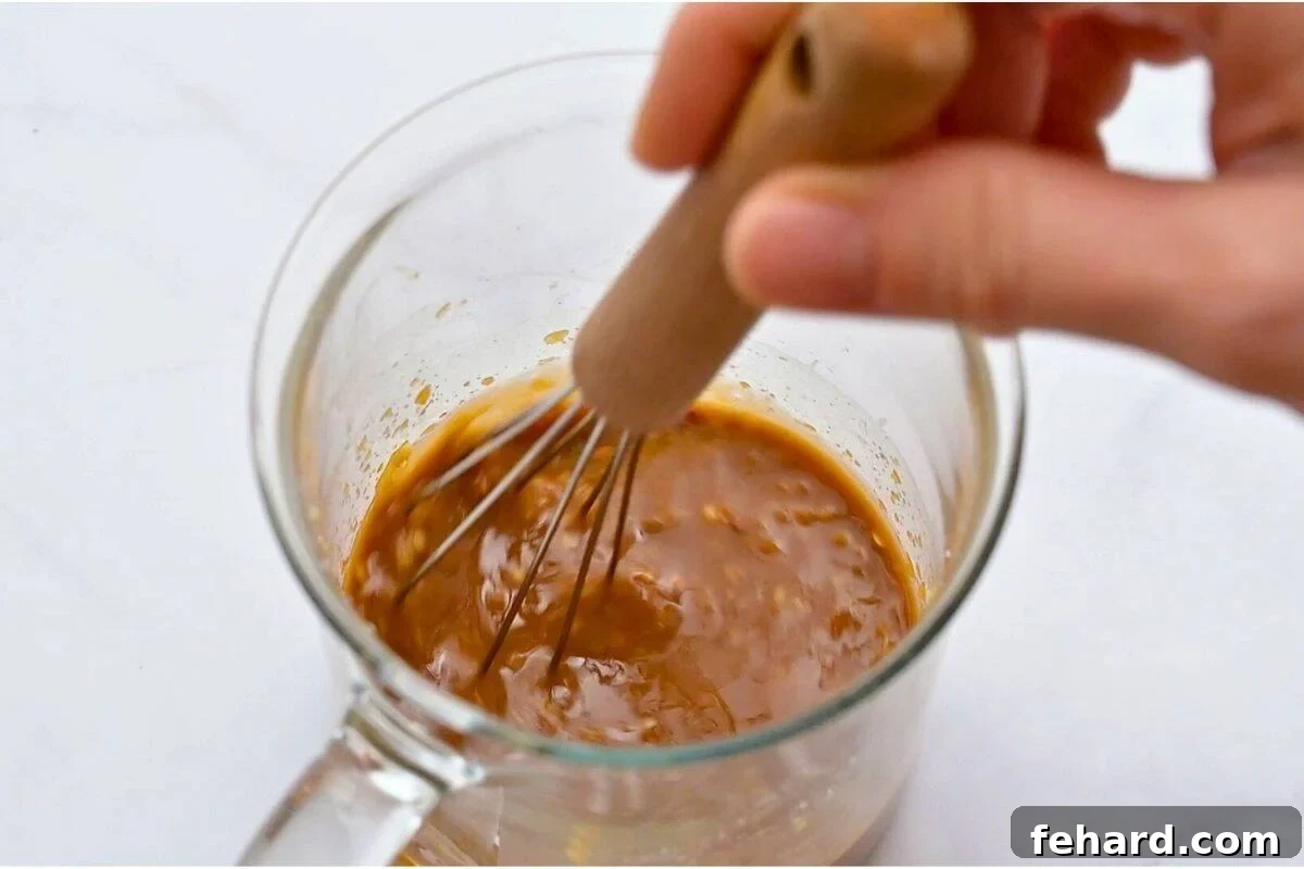 Small glass jar with sauce for beef and broccoli stir fry being whisked together.