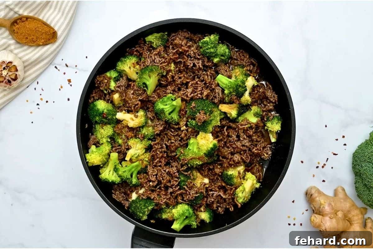 Sautéed ground beef with crisp tender broccoli tossed with sweet and savory sauce in sauté pan.