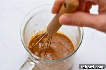 Small glass jar with sauce for beef and broccoli stir fry being whisked together.