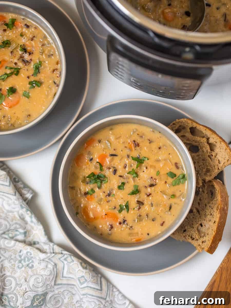 Two steaming bowls of creamy Instant Pot Wild Rice Soup, garnished with fresh parsley, served alongside crusty bread with an Instant Pot visible in the background. Perfect for a cozy meal.