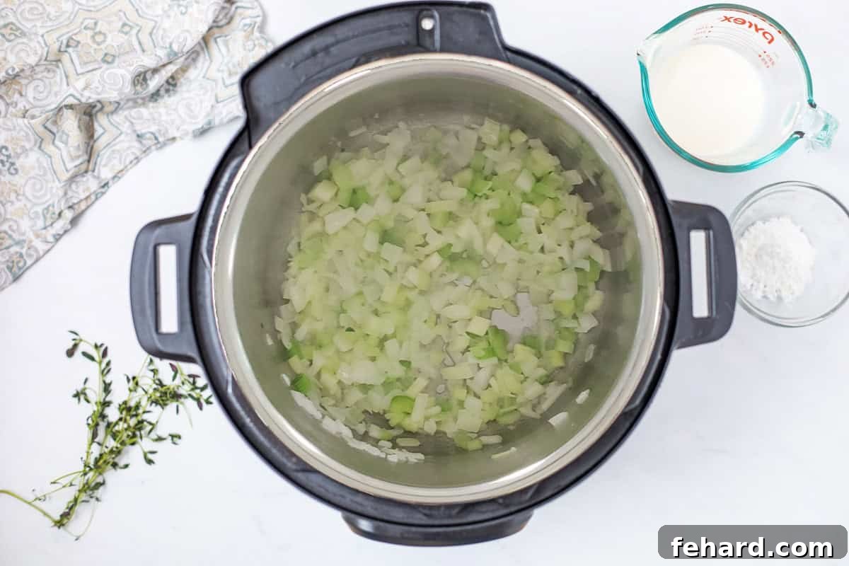 Softened diced yellow onions and celery sautéing in melted butter inside the Instant Pot's inner pot, forming the aromatic base for wild rice soup.