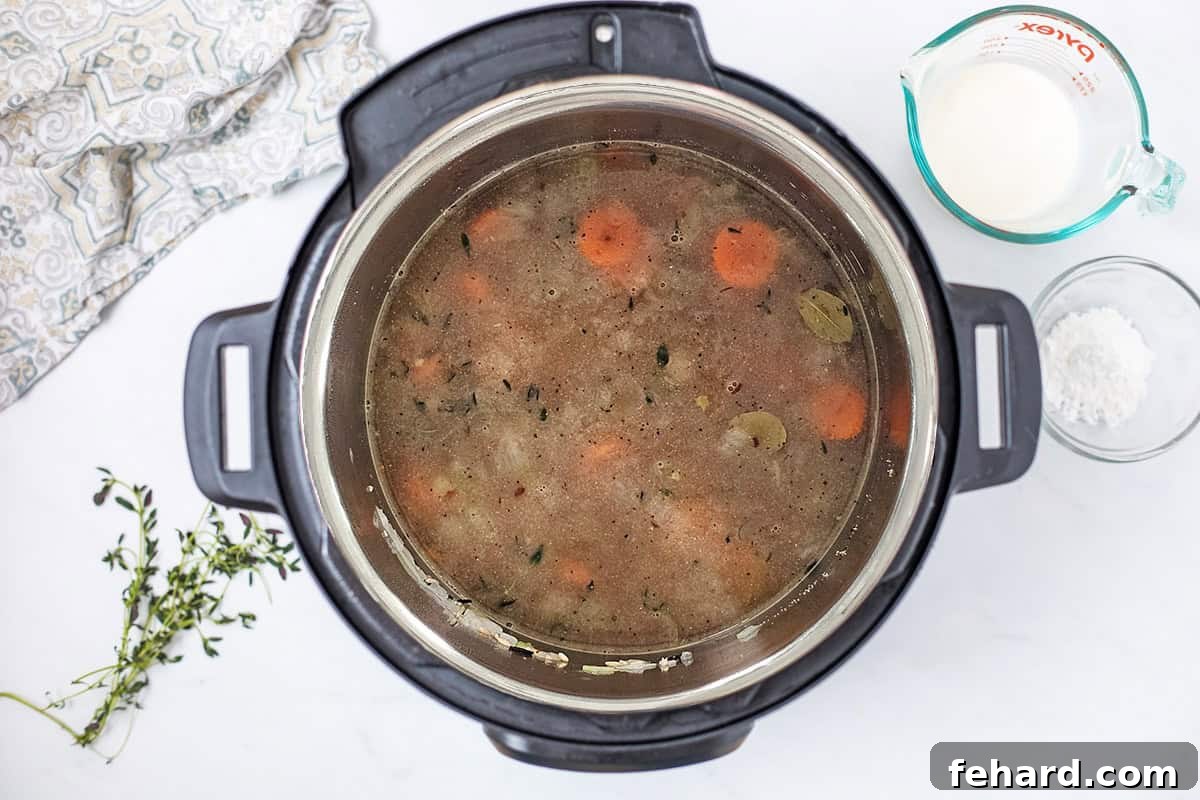All primary ingredients for wild rice soup, including broth, wild rice, sautéed vegetables, and aromatic herbs, layered inside the Instant Pot's inner pot, ready for pressure cooking.