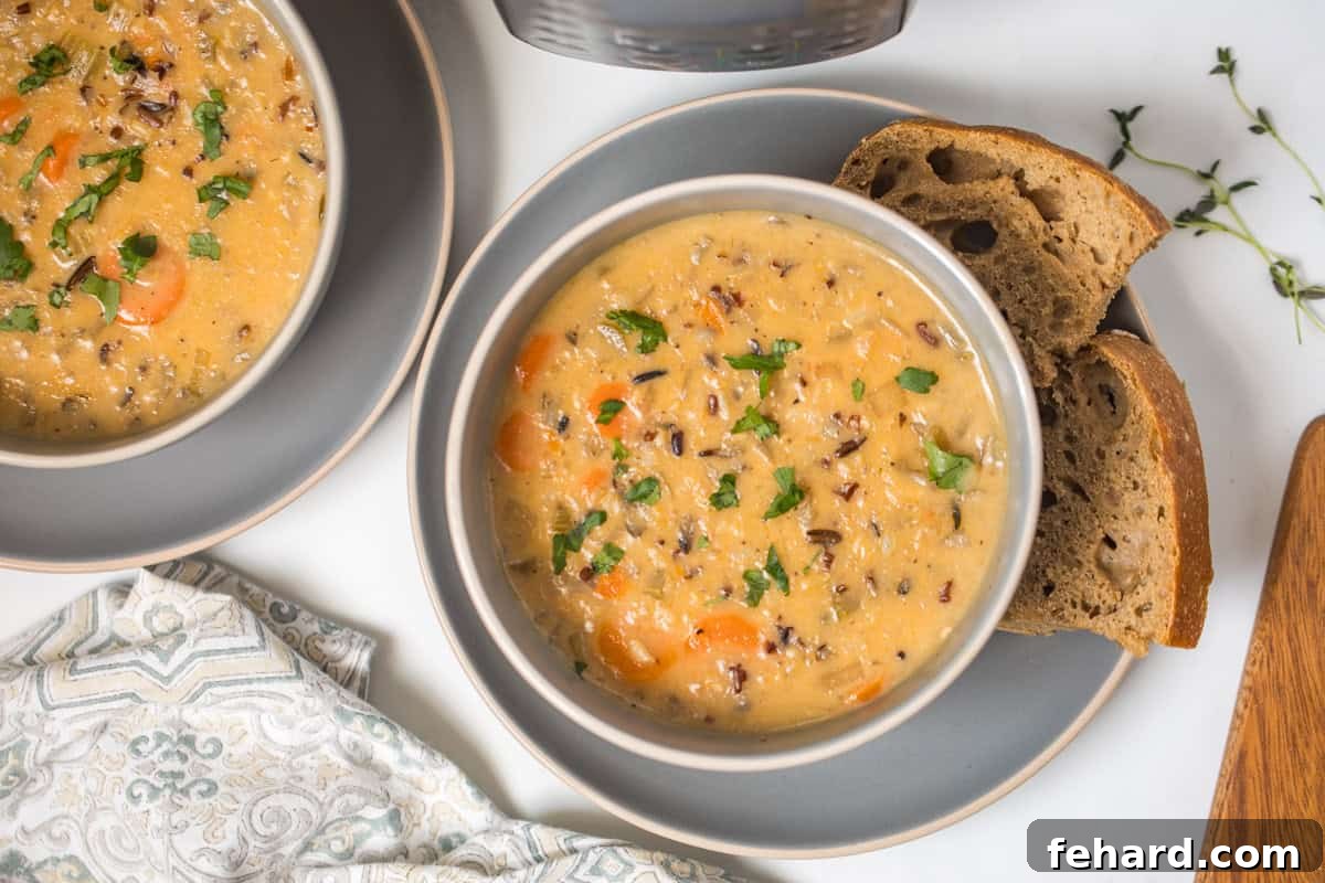 Two artfully arranged bowls of Instant Pot Wild Rice Soup, topped with fresh parsley, served with generous slices of rustic bread and the Instant Pot subtly blurred in the background.