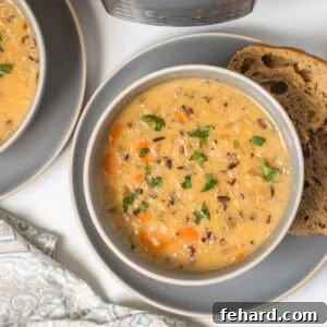 Bowl of creamy vegetarian Instant Pot Wild Rice Soup in grey bowl topped with parsley served with hearty bread.