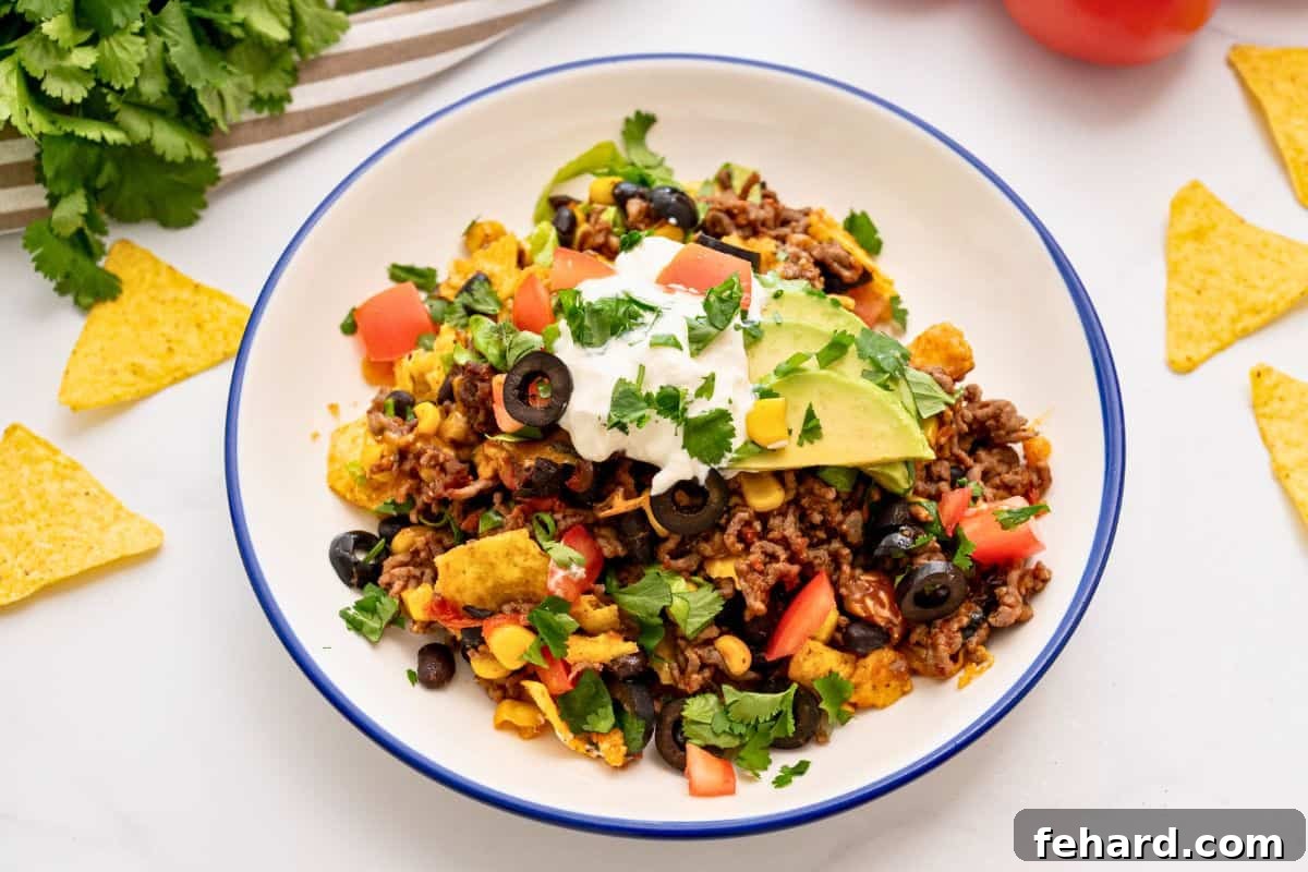 Easy Taco Casserole Recipe for Families A generous serving of ground beef and bean taco casserole, topped with fresh lettuce, vibrant cilantro, diced tomatoes, and creamy sliced avocado, ready to be enjoyed.