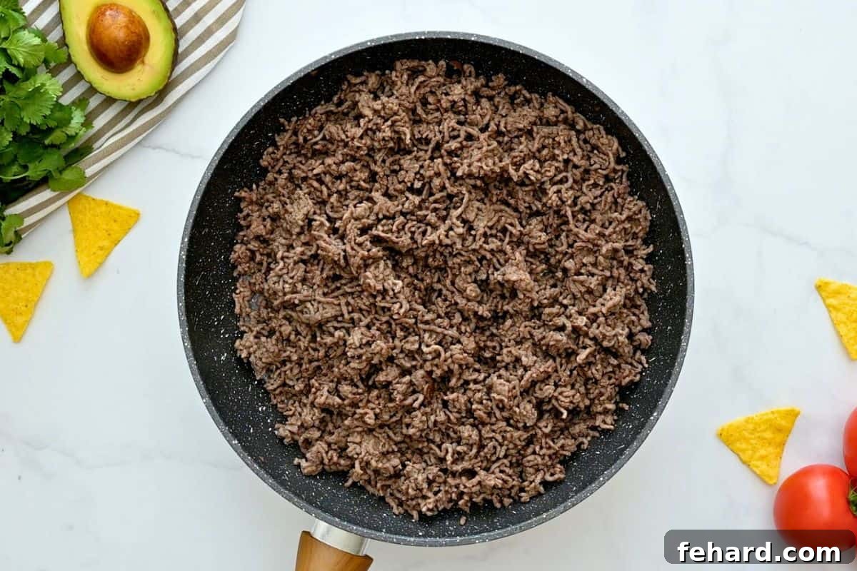 Taco Bake Recipe Preparation Perfectly cooked and crumbled ground beef in a skillet, forming the flavorful base for a hearty taco casserole.
