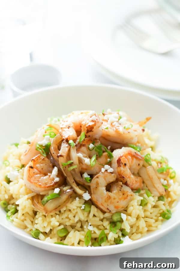 Rice with Balsamic Onions and Shrimp in a white bowl, garnished with fresh herbs