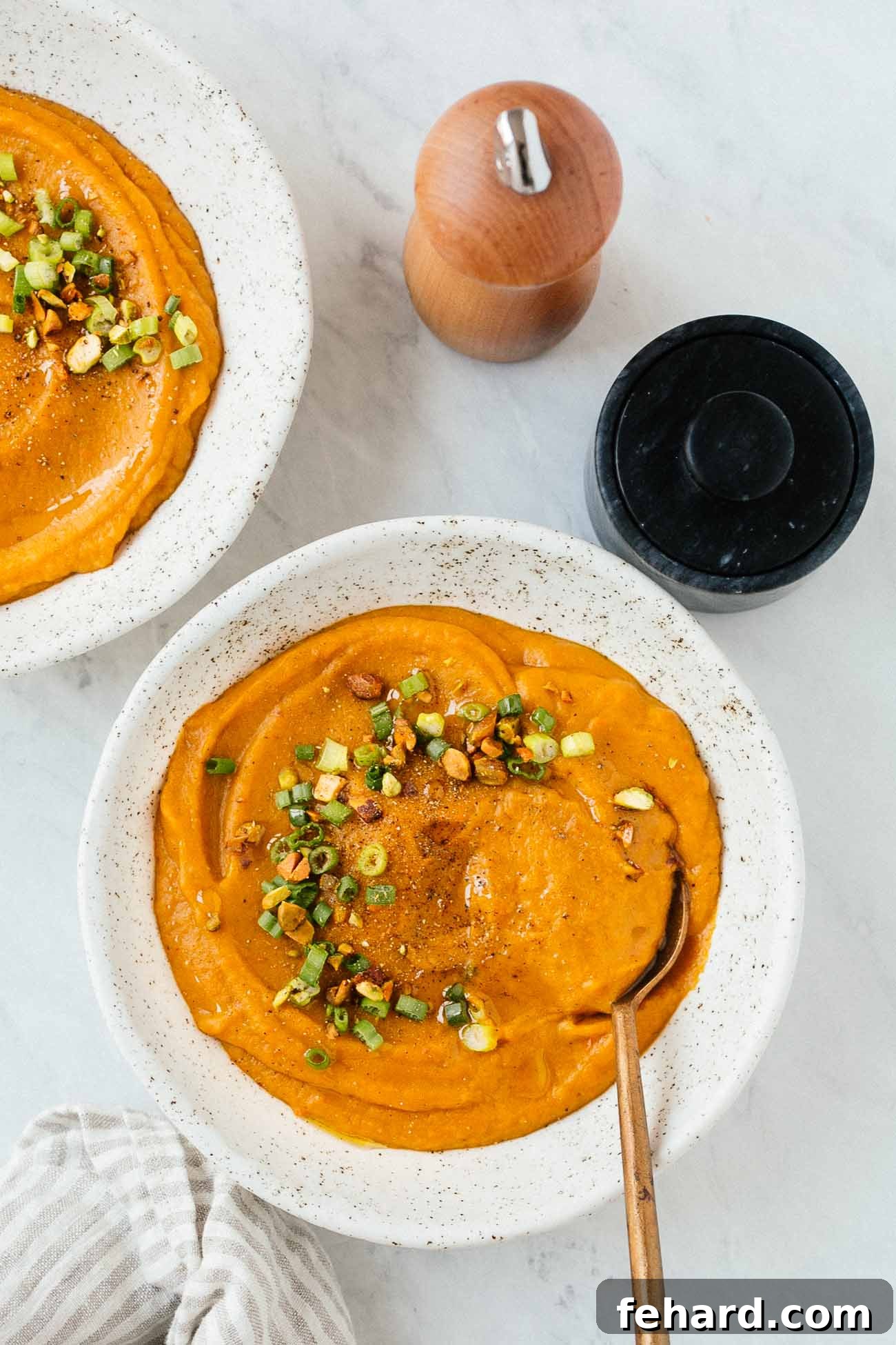 Comforting Carrot Leek Soup 2 Overhead image focusing on one of two bowls of carrot leek soup in white bowls.
