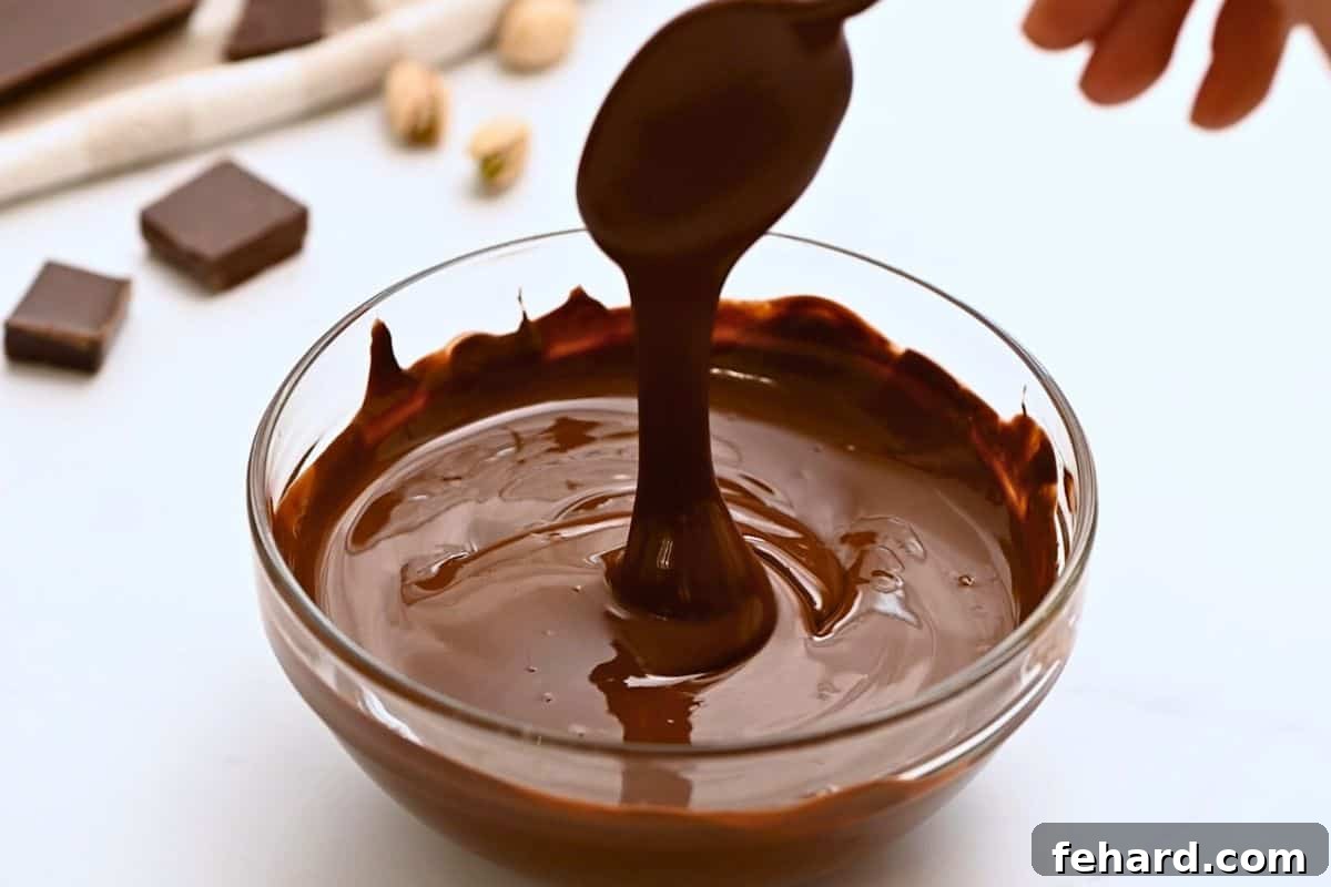 Silky melted dark chocolate being poured, showcasing its rich, glossy texture, perfect for forming the base of your chocolate bark.