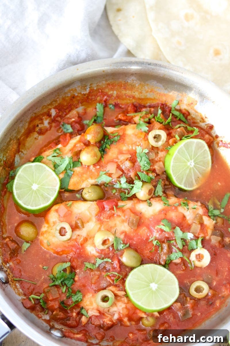 Easy Fish Veracruz Skillet Dinner Skillet with perfectly cooked tilapia fillets in a rich, vibrant Veracruz sauce, garnished with fresh cilantro and lime slices.