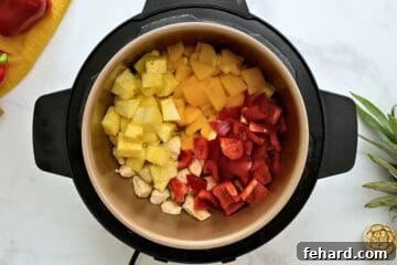 Chicken, pineapple, peppers, and onions layered together inside instant Pot.