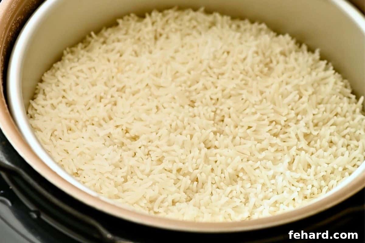Fluffy white rice cooked pot-in-pot, resting above the sweet and sour chicken in the Instant Pot.