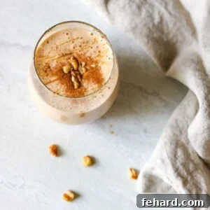 A refreshing glass of sweet potato smoothie, beautifully topped with a delicate sprinkle of cinnamon and a scattering of crushed walnuts for added texture and flavor.