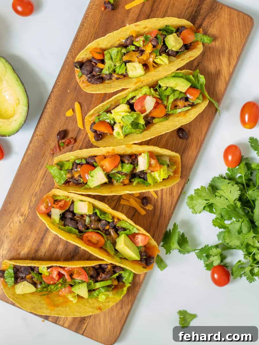 Delicious Black Bean Tacos arranged on a rustic wooden cutting board, generously topped with fresh diced tomatoes, crisp lettuce, vibrant cilantro, and creamy avocado slices. A perfect image showcasing a healthy, quick, and flavorful meal.