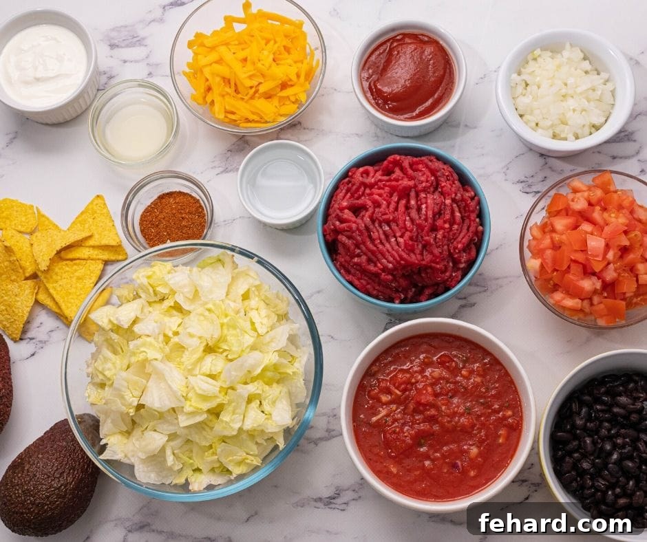 Taco Salad Ingredients A vibrant selection of fresh ingredients laid out on a kitchen counter, including crisp lettuce, ripe avocados, juicy tomatoes, shredded cheese, beans, and seasoned ground meat, ready for an easy Taco Salad recipe.