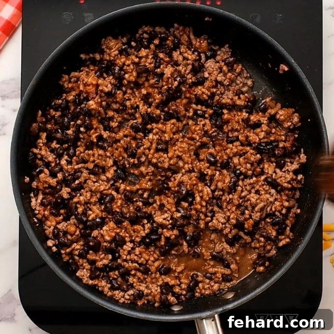 How to Prepare Taco Meat for Salad Skillet filled with perfectly seasoned taco meat and black beans, ready to be added to the Taco Salad. The meat is browned to perfection, and the beans are infused with rich flavors.