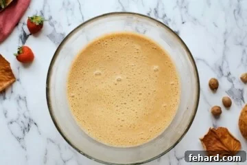 Mixing bowl with eggs, maple syrup, cinnamon, nutmeg, and vanilla mixed together.