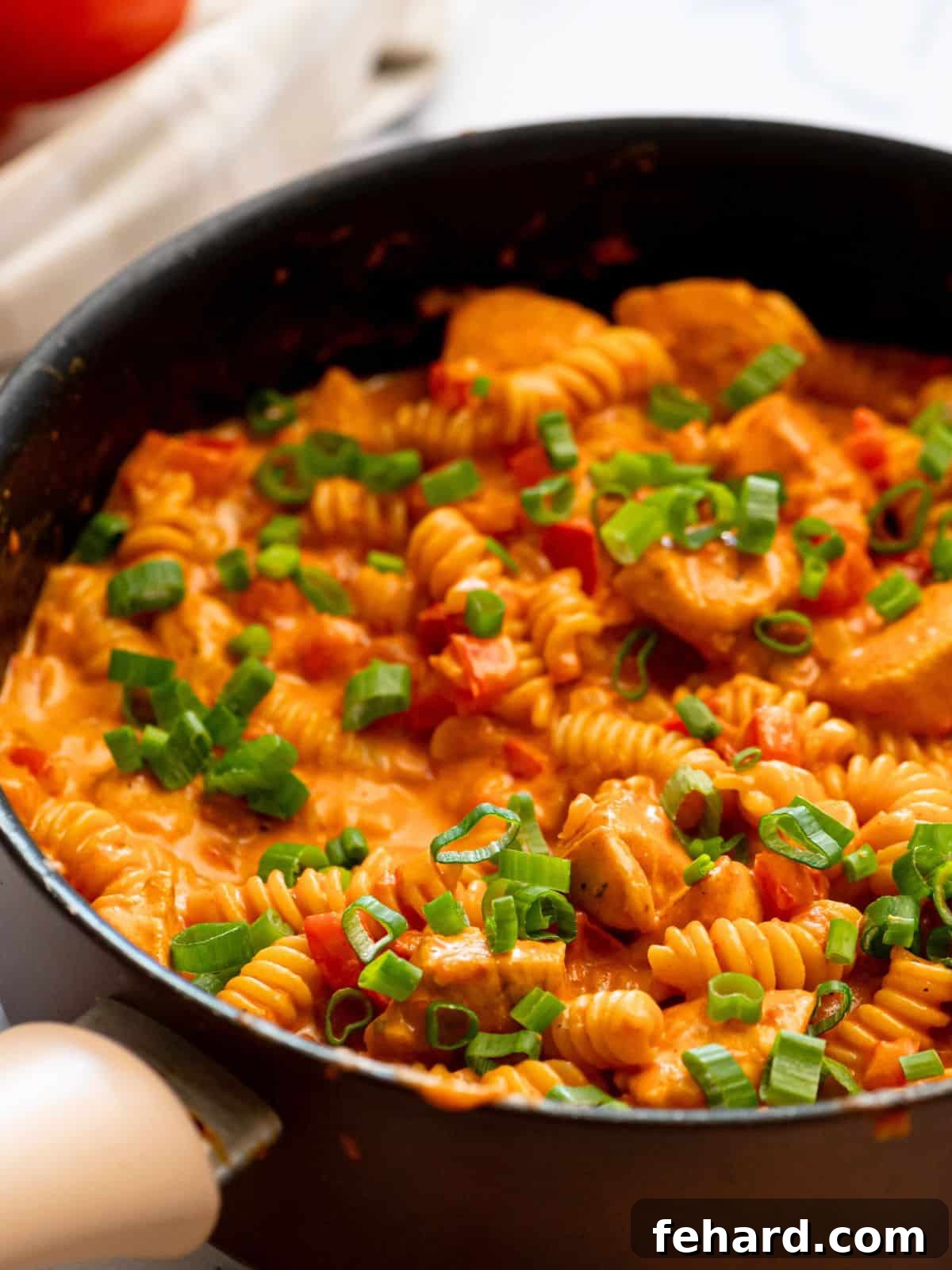 Creamy Cajun Chicken Pasta in a large skillet, beautifully garnished with fresh green onions, ready to serve.