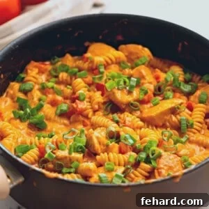 Skillet with Creamy Chicken Cajun Pasta topped with green onions.