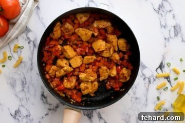 Sautéing chicken, onions, and bell peppers in a skillet.