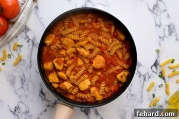 Pasta, chicken, and Cajun sauce simmering in a skillet.