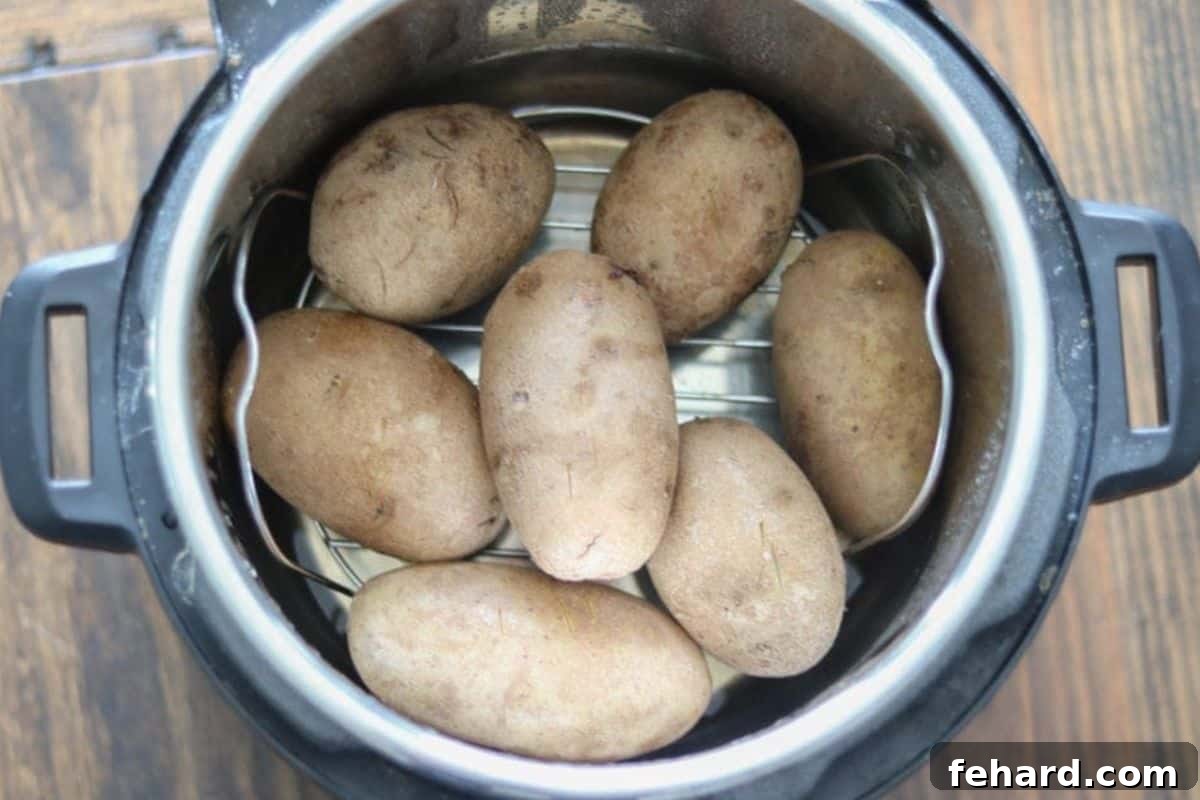 Several perfectly baked potatoes resting on a metal trivet inside an Instant Pot, showing their tender, ready-to-eat appearance with visible steam, indicating their fresh-cooked state.