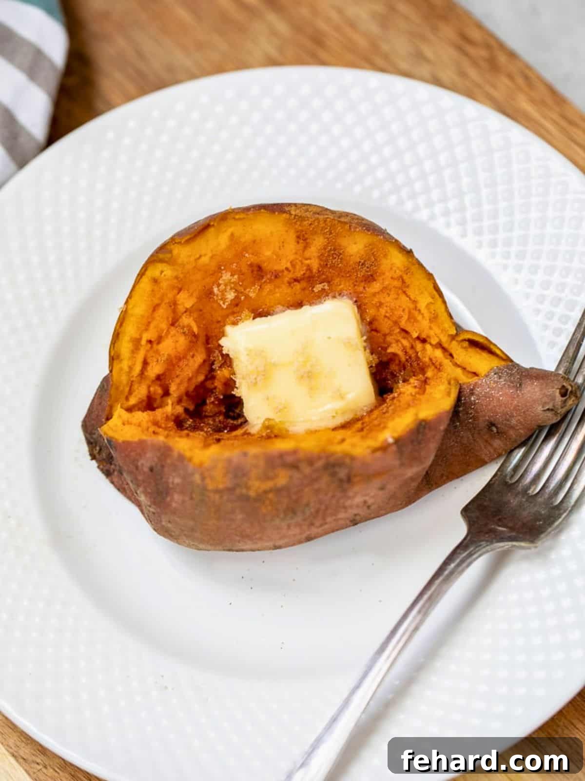 Perfectly cooked Instant Pot sweet potato, cut open to reveal a fluffy, creamy interior, served on a white plate topped with a pat of butter and a sprinkle of cinnamon, ready to be enjoyed.