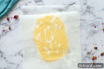 Sugar cookie dough between two sheets of parchment paper dusted with powder sugar.