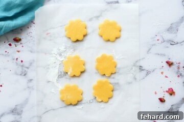 Sugar Cookie dough cut into flowers on parchment paper.