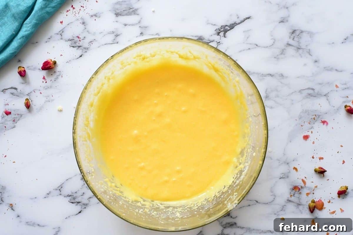 Large mixing bowl filled with perfectly creamed butter, sugar, eggs, and vanilla extract, ready for dry ingredients.