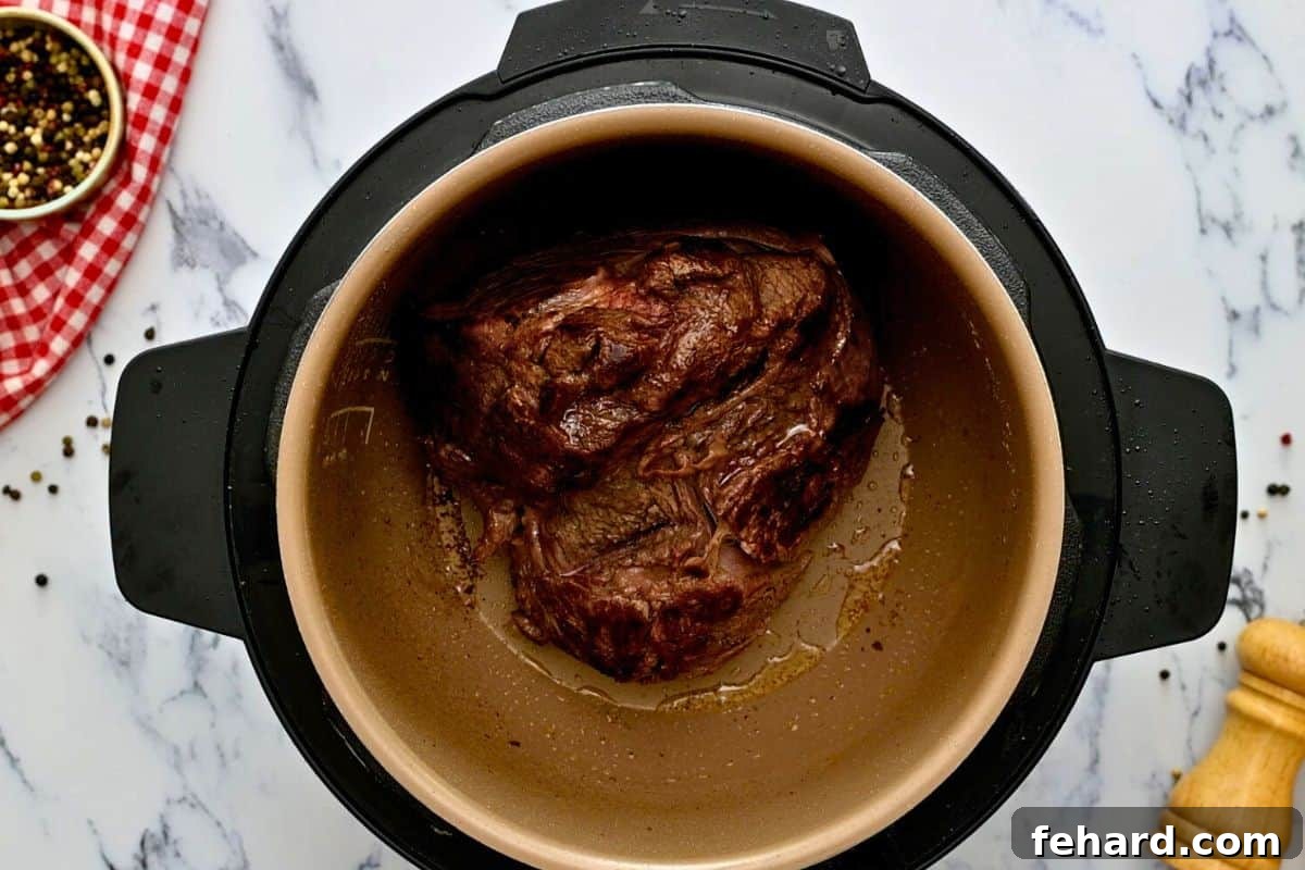 Seasoned chuck roast after being seared to a golden-brown perfection inside the Instant Pot's inner pot.