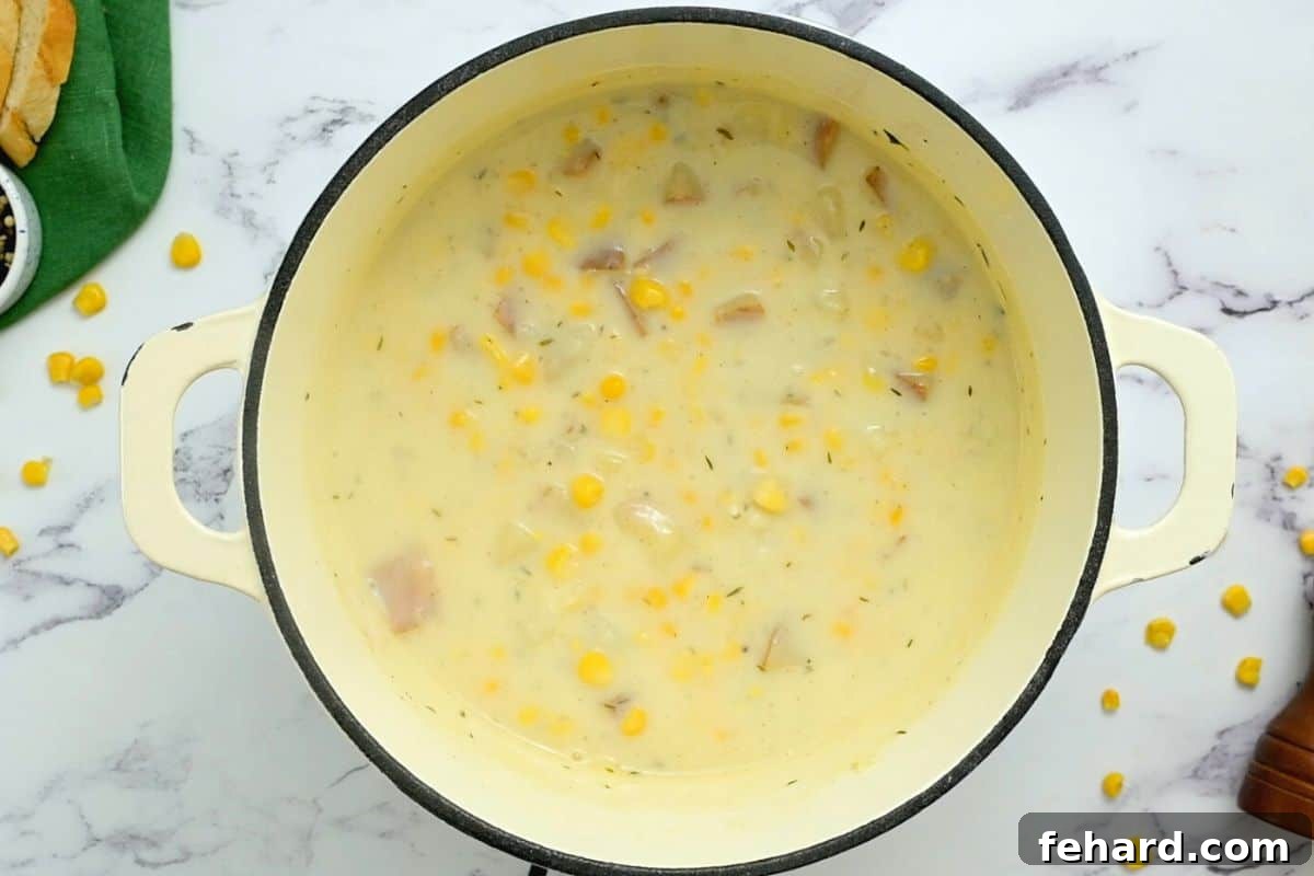 Rich and creamy potato corn chowder after thickening, ready to be served in a warm bowl.