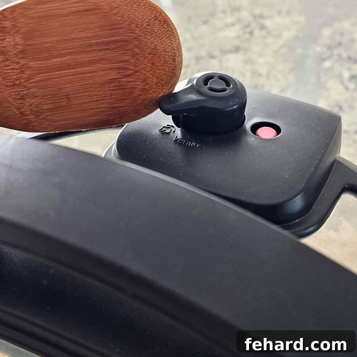 Wooden spoon knocking venting knob from sealed to venting position on Instant Pot lid.
