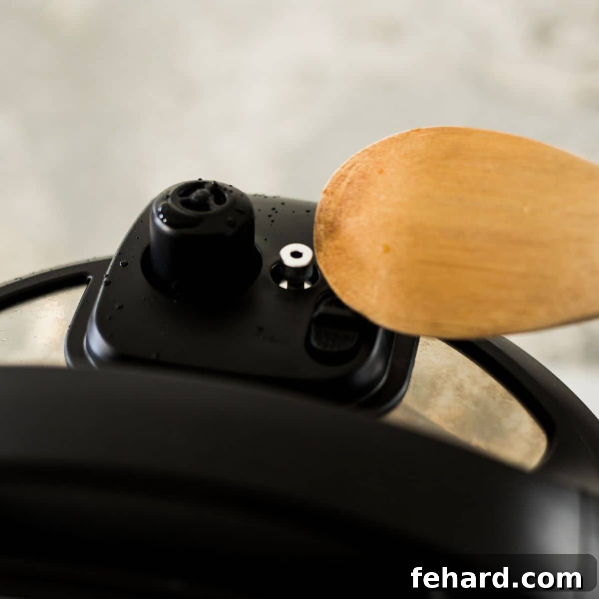 Wooden spoon knocking venting knob from sealed to venting position on Instant Pot lid.