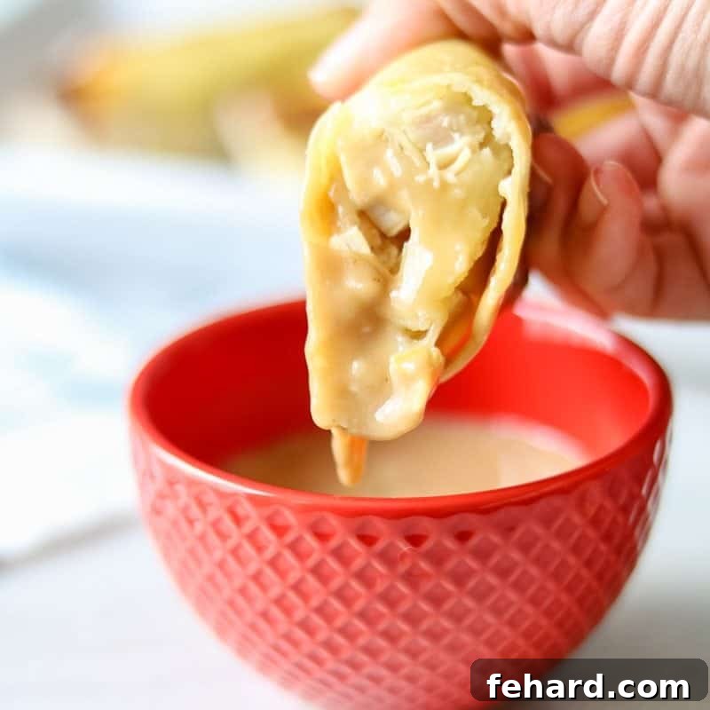 A crispy baked egg roll stuffed with potatoes, turkey, and mashed potatoes dipping into gravy. 
