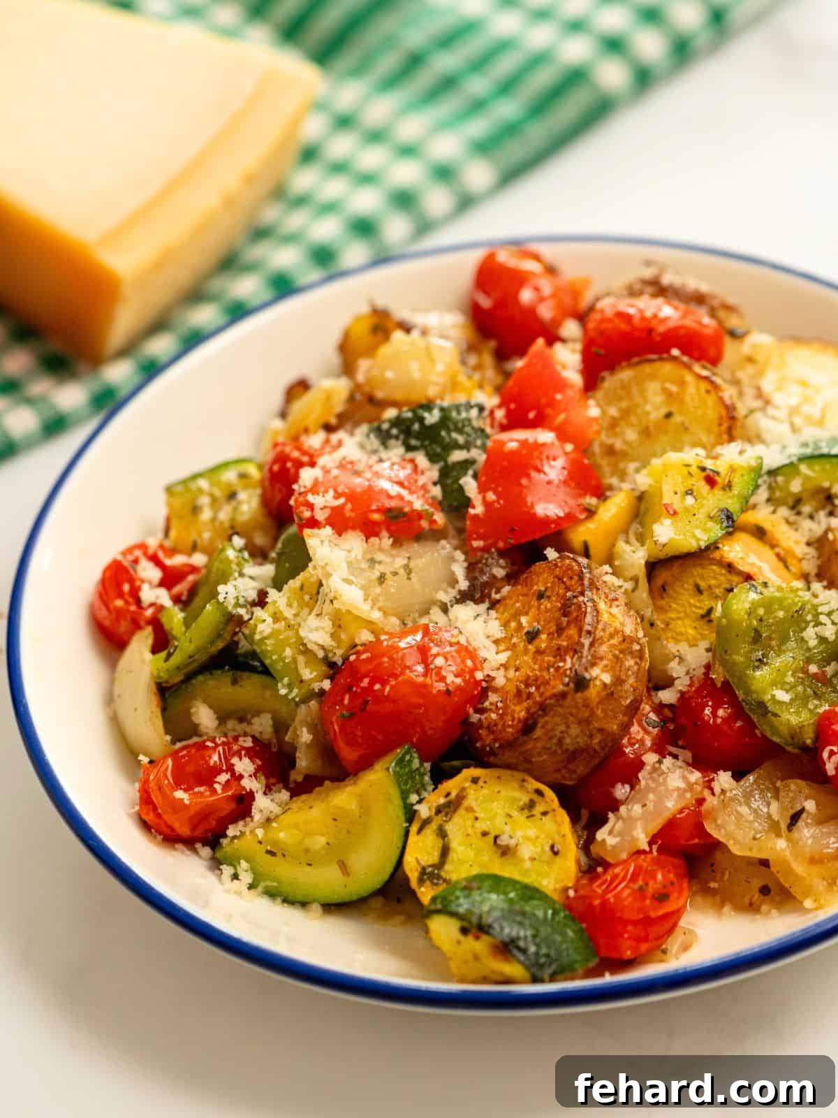 Delicious Roasted Italian Vegetables with Parmesan Roasted Italian Vegetables dished up in a blue and white bowl, generously topped with freshly grated parmesan cheese, highlighting the golden-brown caramelization of the veggies.
