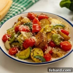 Mediterranean Roasted Vegetables 3 Roasted Italian-flavored potatoes and Vegetables dished up in blue and white bowl topped with parmesan cheese, highlighting vibrant colors and textures.