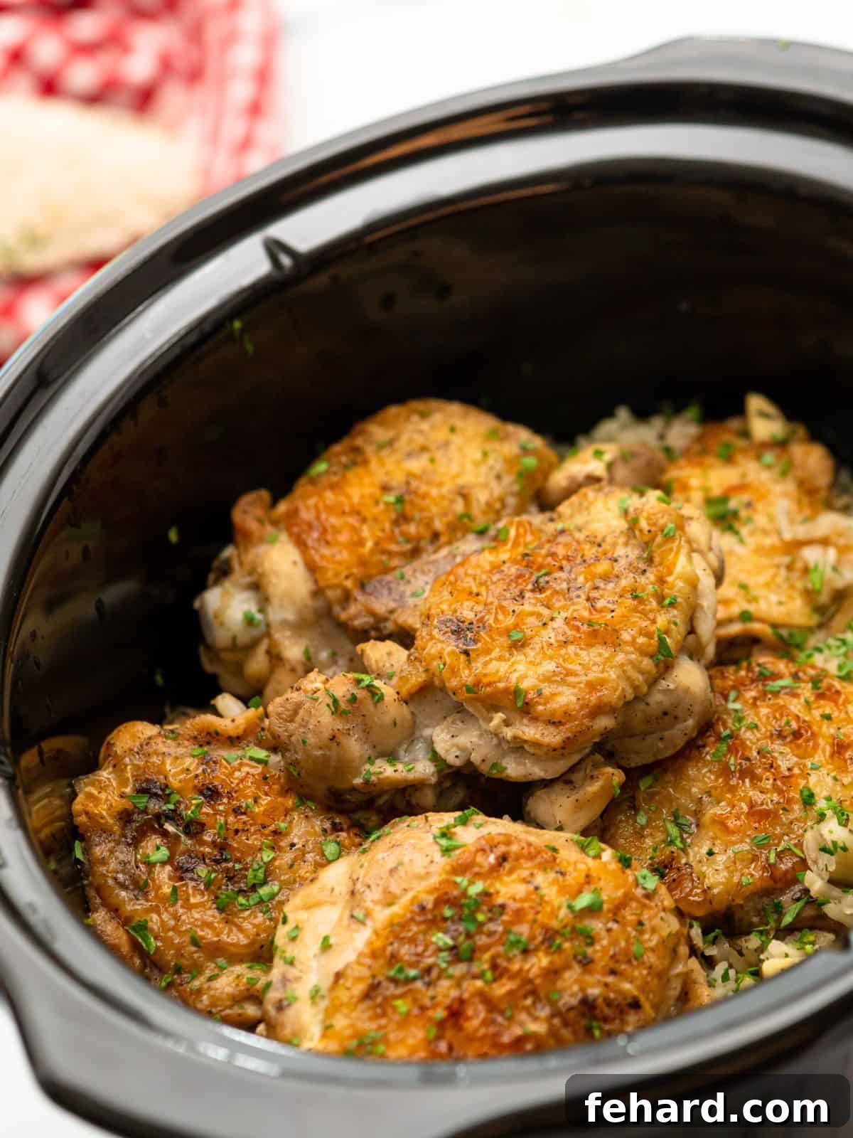 A slow cooker filled with perfectly cooked rice and golden-brown seared chicken thighs, glistening and ready to be served.