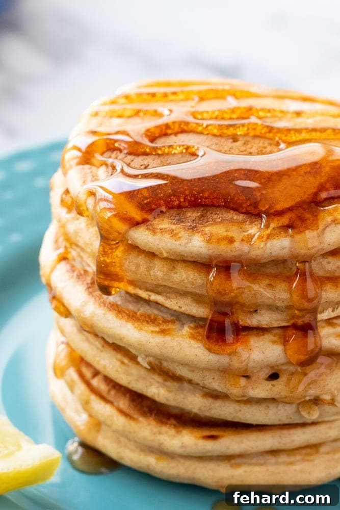 Stack of Golden Brown Fluffy Whole Wheat Pancakes drizzled generously with Maple Syrup.