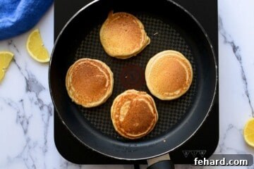 Freshly flipped whole wheat pancakes cooking on a griddle, golden brown and fluffy.