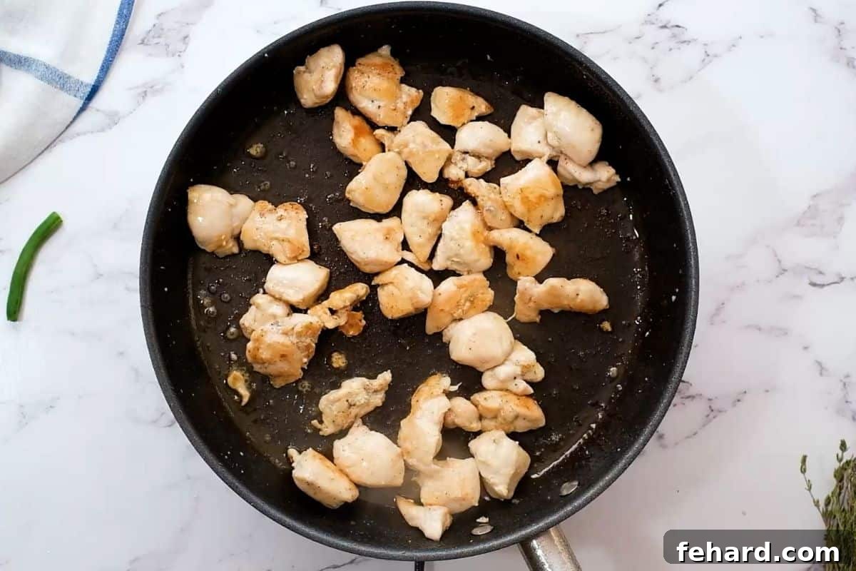 Easy Chicken Breast Recipe with Green Beans Step 1 Bite-sized chicken breast pieces browning in a hot skillet with olive oil.
