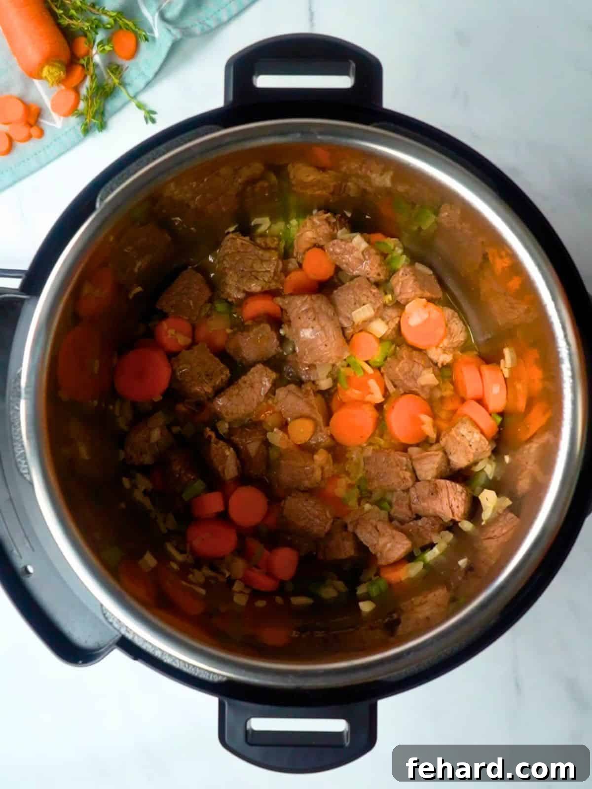 Perfectly seared beef and sautéed vegetables simmering in the Instant Pot, forming a flavorful base for the soup.