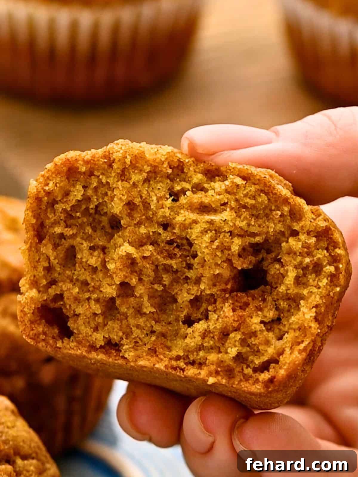 A healthy whole wheat, dairy-free pumpkin muffin cut in half to showcase its fluffy and soft interior texture.
