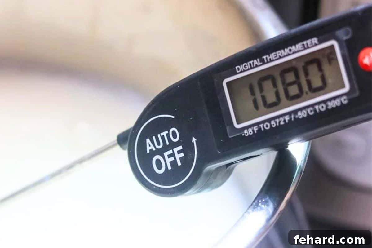 Digital thermometer inserted into the inner pot, showing milk cooled to 108 degrees F, ready for yogurt starter.