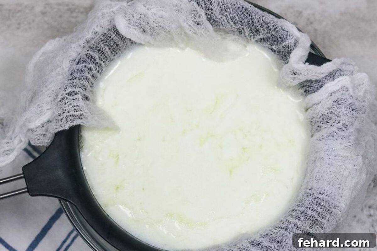Instant Pot yogurt being strained through cheesecloth over a fine mesh strainer and bowl.