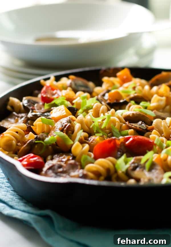 Close up shot of cooked fusilli with mushroom and roasted butternut squash in a bowl.