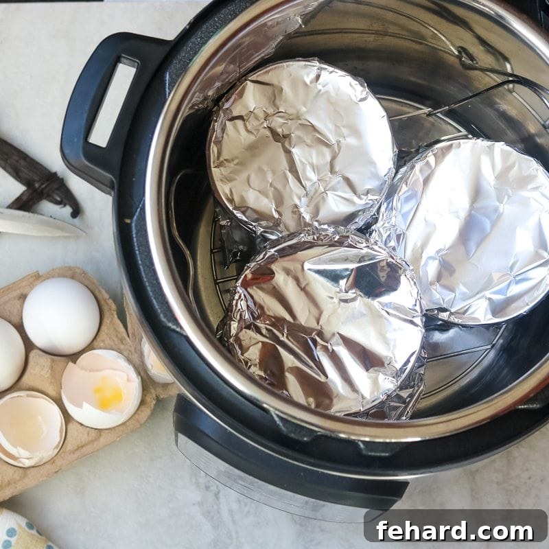 Properly placing ramekins inside the Instant Pot for even and consistent cooking. Three custard cups, each securely covered with aluminum foil, arranged neatly on a metal trivet inside the Instant Pot, ready for pressure cooking.