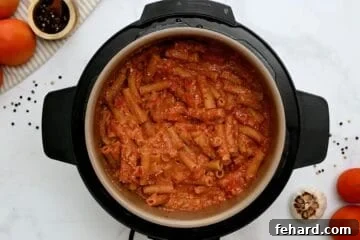 Ziti cooked with tomato sauce and ricotta stirred together inside inner pot of electric pressure cooker.
