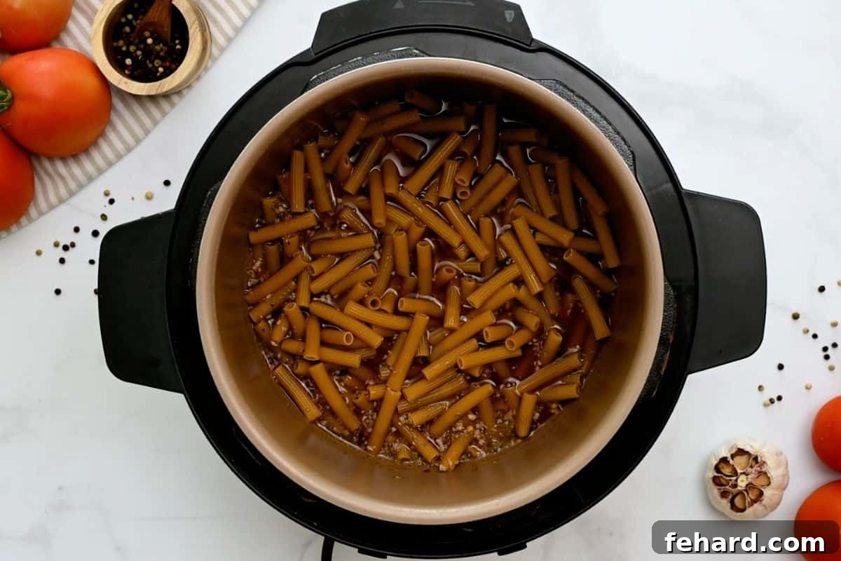 Stock, wine, seasonings, and ziti noodles carefully layered inside the Instant Pot, showing the base liquid.